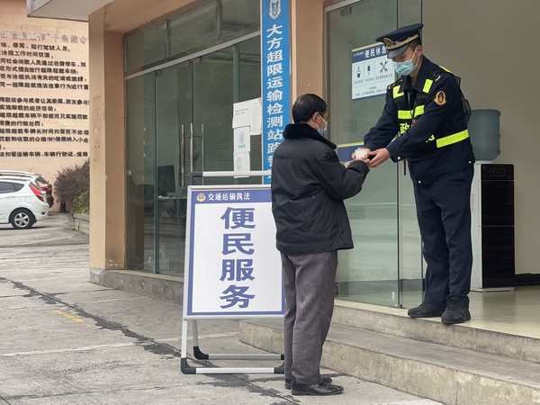 貴畢公路大方超限站執(zhí)法人員給過(guò)往貨車司機(jī)倒熱水。