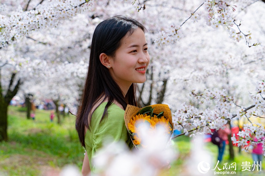 游客站在花叢中與櫻花合影留念。人民網(wǎng) 陽茜攝